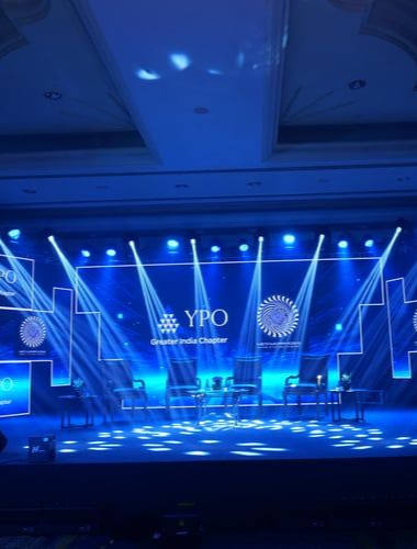 Corporate stage event with a branded backdrop and dramatic lighting, produced by The Velvet Desk Global